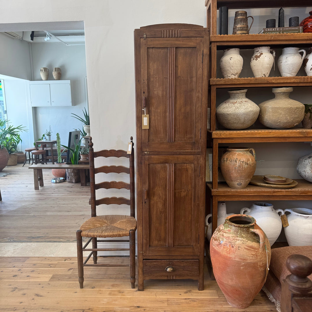Wooden cabinet and shelves with decorative jars and a chair in a room setting.